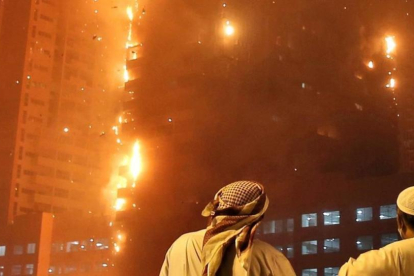 Dos oficiales emiratíes miran como se estiende el fuego a lo largo del edificio.-Kamran Jebreili