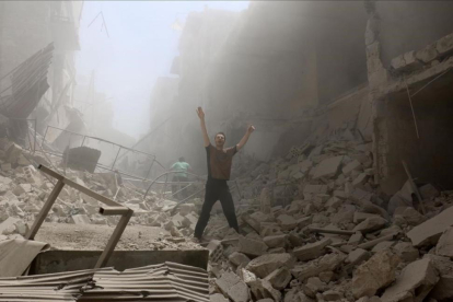 Un hombre pide ayuda en medio de los escombros de los edificios destruidos en una calle de Alepo.-AFP / AMEER ALHALBI