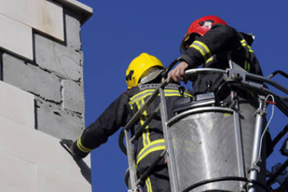 Varios bomberos retiran parte de una fachada para garantizar la seguridad. / VALENTÍN GUISANDE-