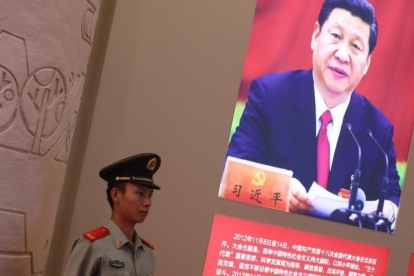 Un agente de policía permanece junto a una foto del presidente Xi Jinping, exhibida en una exposición sobre los logros de China en los últimos cinco años, en Pekín.-EFE / WU HONG