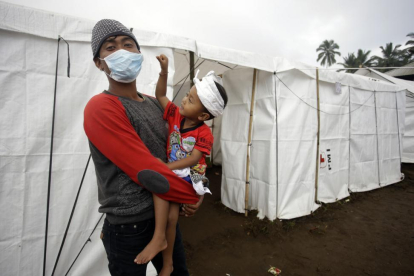 Un padre y su hijo tras ser evacuados a causa de la erupción del volcán Agung.-/ FIRDIA LISNAWATI / AP