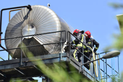 Dos bomberos, ayer, trabajando en las labores de extinción del incendio declarado en la empresa Tableros Losán. / ÁLVARO MARTÍNEZ-