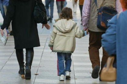 Unos padres pasean con su hijo, cogidos de la mano.-RICARD CUGAT