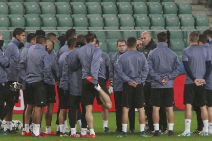 Los jugadores del Madrid escuchan a Zidane en el entrenamiento en el Ejército Polaco, campo del Legia.-AP / CZAREK SOKOLOWSKI
