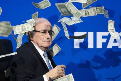 Joseph Blatter, rodeado de billetes lanzados por un espontáneo durante una rueda de prensa en la sede de la FIFA en Zúrich.-AFP / FABRICE COFFRINI