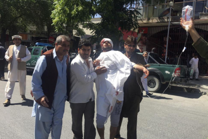 Tres personas ayudan a un hombre herido en el atentado de este miércoles en Kabul.-AP / RAHMAT GUL