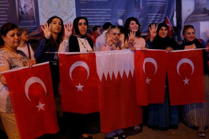 Mujeres con banderas turcas y qatarís en Estambul.-REUTERS / MURAD SEZER