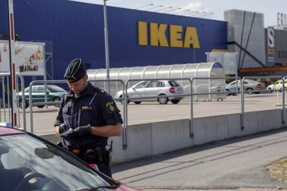 Un agente habla con unos clientes en las afueras del Ikea de Vasteras, en Suecia.-Foto: AP / PETER KRUGER