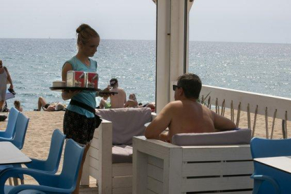 Una camarera en un chiringuito de playa trabajando durante el verano, en Badalona.-MAITE CRUZ (EL PERIÓDICO)