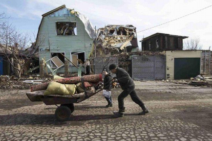 Un hombre empuja una carretilla ante una vivienda destruida por los combates en la ciudad de Debáltsevo , Ucrania.-Foto: REUTERS / BAZ RATNER