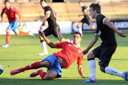 Carlos Akapo trata de frenar el avance de un jugador del Burgos. / ISRAEL L. MURILLO-