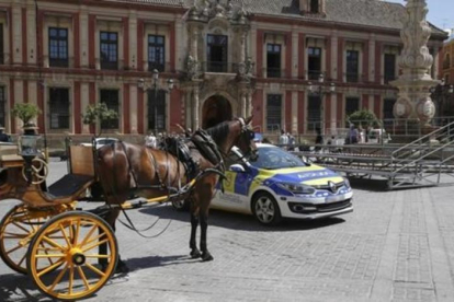 Un coche de caballos y una patrulla policial junto a una de las tribunas, en la Plaza de la Virgen de los Reyes, que estaban preparadas para la visita del presidente de EEUU Barack Obama a Sevilla, que finalmente ha sido cancelada-EFE / JULIO MUÑOZ