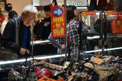 Un ciudadano japonés mira bolsos en una tienda en Tokio.-AFP / YOSHIKAZU TSUNO