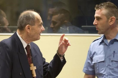 Tolimir (izq), condenado por la masacre de Srebrenica, habla con un guardia de seguridad de la ONU en el tribunal de La Haya, el pasado 8 de abril.-AP / PETER DEJONG
