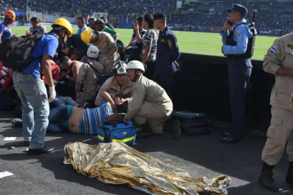 Las asistencias médicas atienden a varios heridos cerca de uno de los dos fallecidos dentro del estadio-AFP