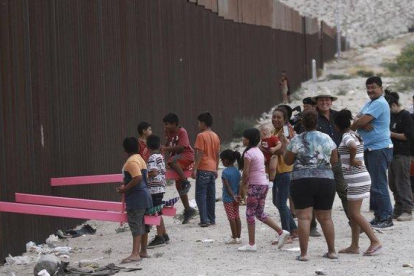 Niños juegan en un balancín situado en el muro de México a su paso por Ciudad Juarez.-AP