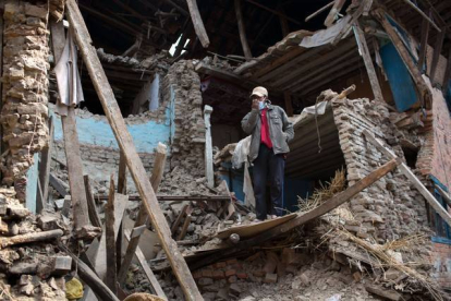Un hombre en pie entre las runas de un edificio destruido por el terremoto de Nepal.-Foto: MENAHEM KAHANA / AFP