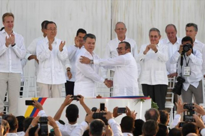 Santos y Timochenko se dan la mano entre los aplausos de Ki-mon, Castro y el rey emérito Juan Carlos, entre otras personalidades.-AFP / LUIS ACOSTA