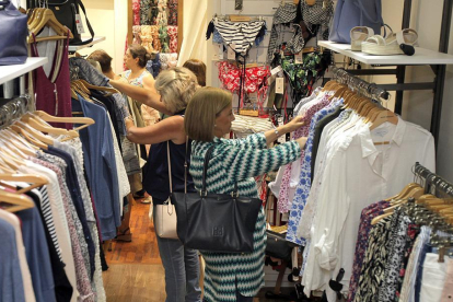 Varias personas observan la ropa expuesta en una tienda.-MARIO TEJEDOR