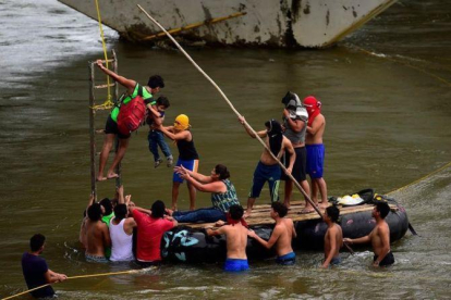 Inmigrantes hondureños socorren a un hombre y un niño en el río Suchiate, en el puente fronterizo de Ciudad Hidalgo, entre Guatemala y México, el 20 de octubre del 2018.-AFP / PEDRO PARDO