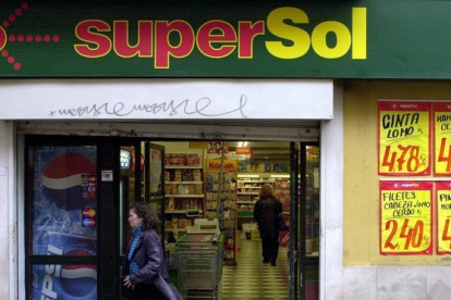 Una cliente sale de un supermercado SuperSol, en una centrica calle de Sevilla.-JULIO MUÑOZ (EFE)
