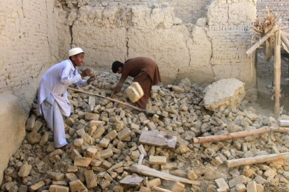 Dos niños afganos mueven los escombros de su vivienda, en el distrito de Nangarhar.-REUTERS / PARWIZ
