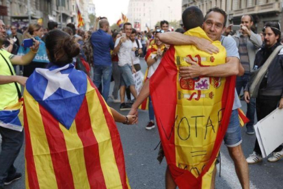 En la imagen una pareja con estelada y bandera española es abrazada por un independentista en Ronda Universitat.-JULIO CARBO