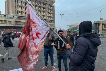 Manifestantes sostienen una bandera manchada de sangre tras el ataque en la plaza Al Jalani de Bagdad.-AP