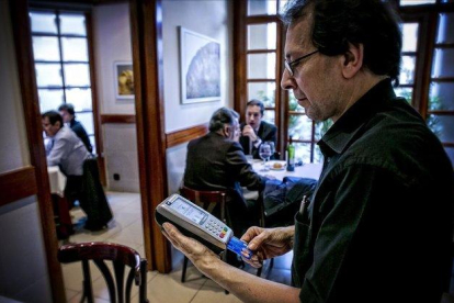 Un camarero cobra una cuenta en un restaurante de Barcelona.-JOAN CORTADELLAS