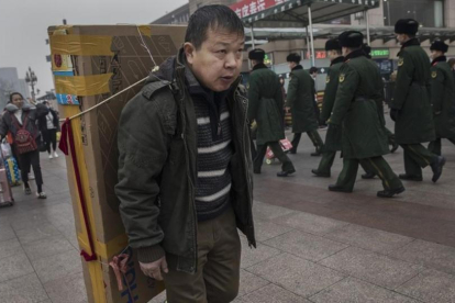 Un hombre llega con un gran televisor en la espalda a la estación central de Pekín, dispuesto a tomar un tren, el 26 de enero.-GETTY IMAGES / KEVIN FRAYER