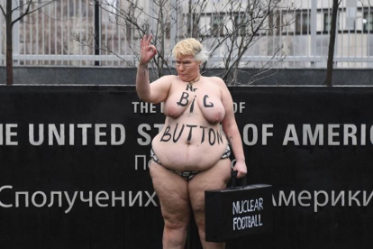 Una activista del movimiento Femen parodia a la mención de Trump sobre el tamño de su botón nuclear, ante la embajada de EEUU en Kiev (Ucrania).-/ AFP / SERGEI SUPINSKY