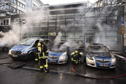 Los bomberos tratan de extinguir las llamas de varios coches de policía incendiados. ODD ANDERSEN | AFP