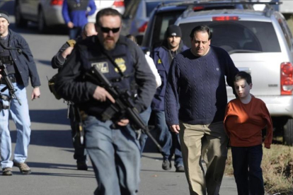 Agentes de policía custodian a padres e hijos de la escuela de Newtown tras la matanza del 2012.-AP / JESSICA HILL