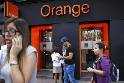 Personas pasan por delante de una tienda de Orange en Madrid.-REUTERS / ANDREA COMAS