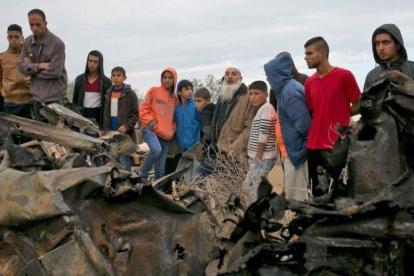 Unos palestinos permanecen junto a los restos de un automóvil destruido tras un ataque aéreo israelí en Khan Yunis, en el sur de la Franja de Gaza.-SAID KHATIB (AFP)