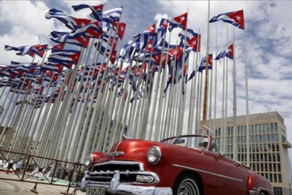 Un coche clásico americano pasa al lado de la embajada estadounidense en La Habana, donde ondean decenas de banderas de Cuba.-AP / DESMOND BOYLAN