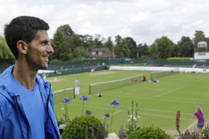 Djokovic observa las pistas de Wimbledon tras el entrenamiento del domingo.-AP / BEN CURTIS