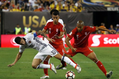 El colombiano James Rodriguez pugna por el balón con los peruanos Alberto Rodriguez y Miguel Trauco.-EFE / JASON SZENES