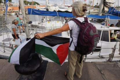 Una activista con la bandera palestina frente a uno de los dos veleros de la flotilla que ha partido hacia Gaza.-JULIO CARBÓ