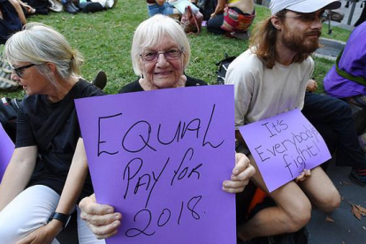 Una australiana pide igual salario para mujeres y hombres, junto a un joven que subraya que es una lucha de todos, en la concentración del Día de la Mujer en Melbourne.-EFE / JOE CASTRO