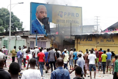 Opositores del presidente Kabila gritan consignas contra el mandatario mientras destruyen un cartel con su imagen, en Kinshasa, capital de la República Democrática del Congo, este lunes.-REUTERS / KENNY KATOMBE