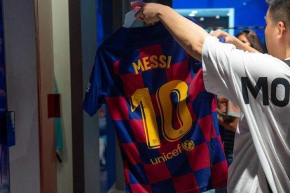 Un aficionado mira una camiseta de Messi, este viernes en la tienda del Barça.-AFP / JOSEP LAGO