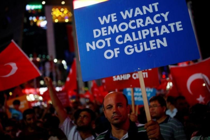 Un hombre sostiene un cartel junto a otros reunidos noche tras noche desde el 15 de julio, día del intento de golpe de Estado, en Ankara, el 27 de julio.-REUTERS / UMIT BEKTAS
