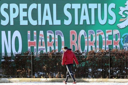 Un peatón pasa junto a un cartel en Belfast sobre el Sinn Féin rechazando una frontera dura.-AFP (PAUL FAITH)