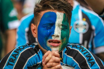 Un aficionado del Gremio llora durante el homenaje al Chapecoense.-AFP / JEFFERSON BERNARDES