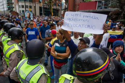 Un grupo de personas protesta frente a miembros de la Policía Nacional Bolivariana (PNB) en la ciudad de Caracas (Venezuela).-EFE / MIGUEL GUTIERREZ