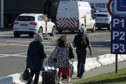 Varias personas caminan hacia la terminal mientras los vehículos hacen cola en un control de seguridad, en el aeropuerto de Zaventem, este lunes.-AFP / THIERRY ROGE