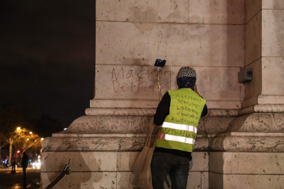Anti-government protester scrawls graffiti that reads  Macron resign   on the wall of the Arc de Triumph in central Paris.-Zakaria ABDELKAFI   AFP
