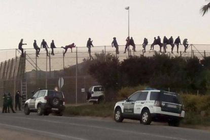 Al menos una quincena de inmigrantes permanecen encaramados en la valla de Melilla en las proximidades del cementerio musulmán.-Foto: EFE / NOELIA RAMOS