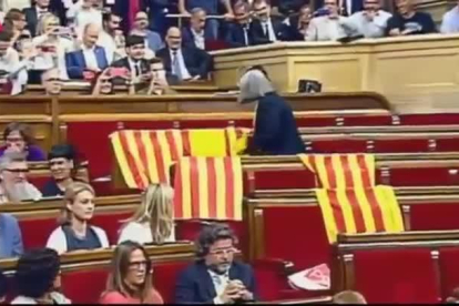 La diputada de Catalunya Sí que es Pot Àngels Martínez retira las banderas de España que habían dejado en su escaño los diputados del PP.-EL PERIÓDICO